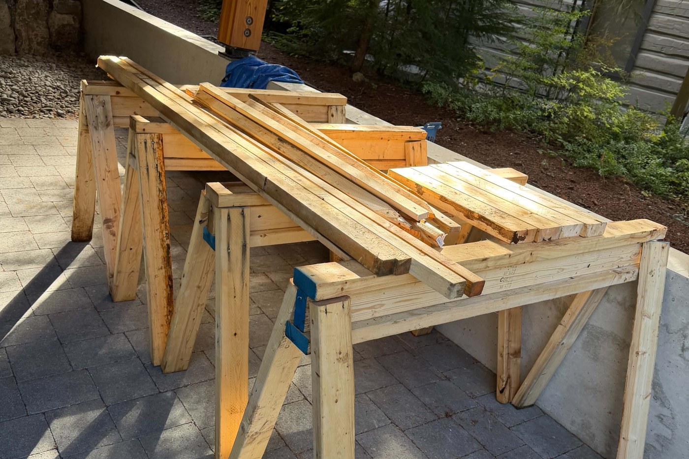 Two wooden sawhorses stacked with cut lengths of lumber